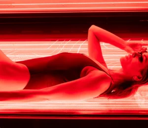Man settling into a red light therapy bed wearing swim shorts and protective eye wear. Man settling into a red light therapy bed wearing swim shorts and protective eye wear.