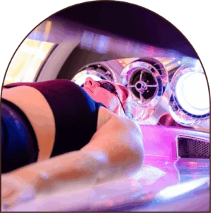 Close-up of a woman lying down in a UV tanning bed wearing a black crop top and protective eye goggles. Close-up of a woman lying down in a UV tanning bed wearing a black crop top and protective eye goggles.