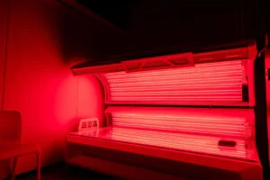 Full-body red light therapy bed illuminated inside a private treatment room at The Tanning Shop Ireland