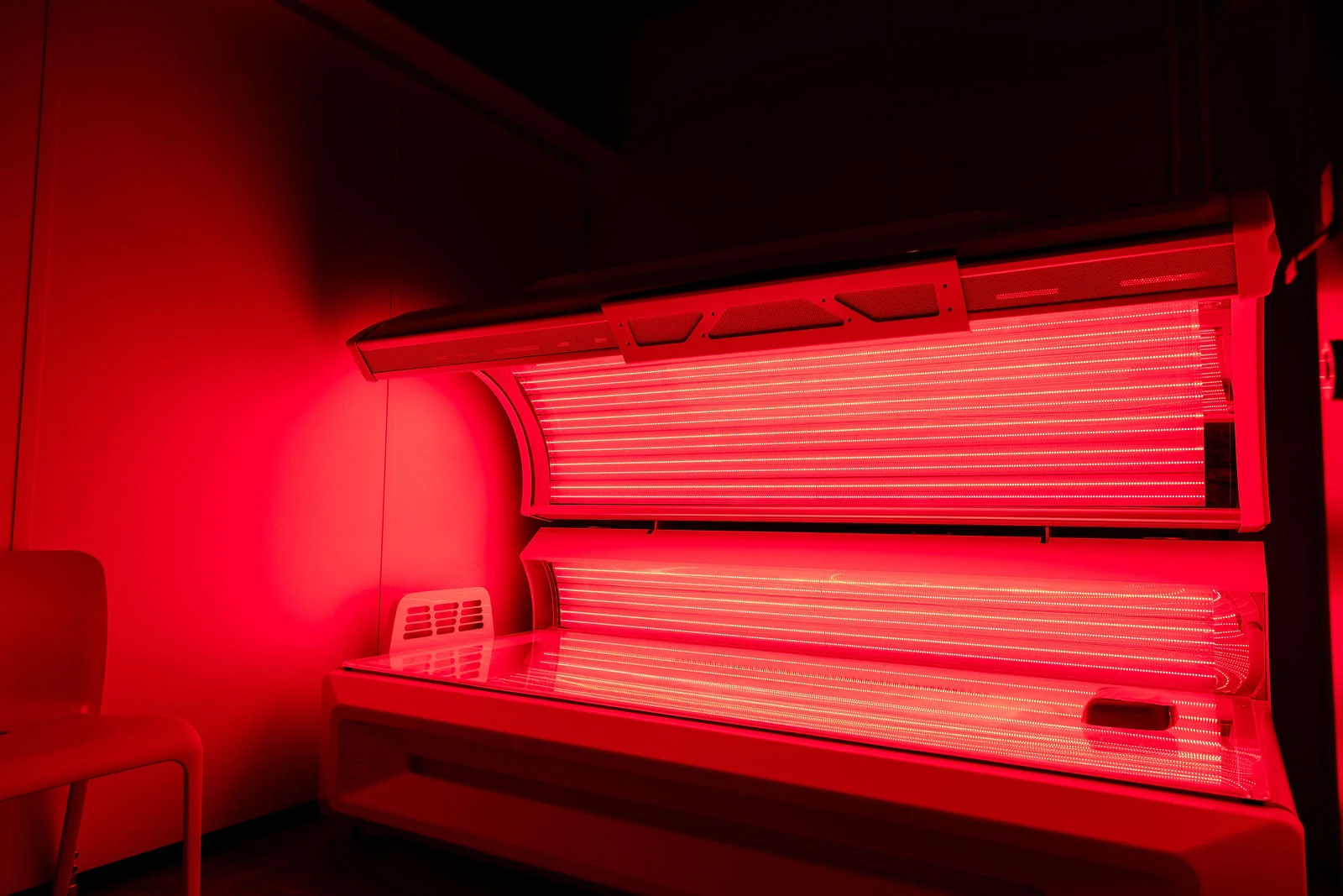 Full-body red light therapy bed illuminated inside a private treatment room at The Tanning Shop Ireland
