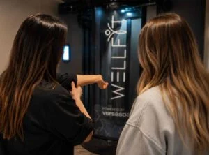 Tanning Shop consultant giving a free personalised WellFit skincare consultation to a customer in salon.