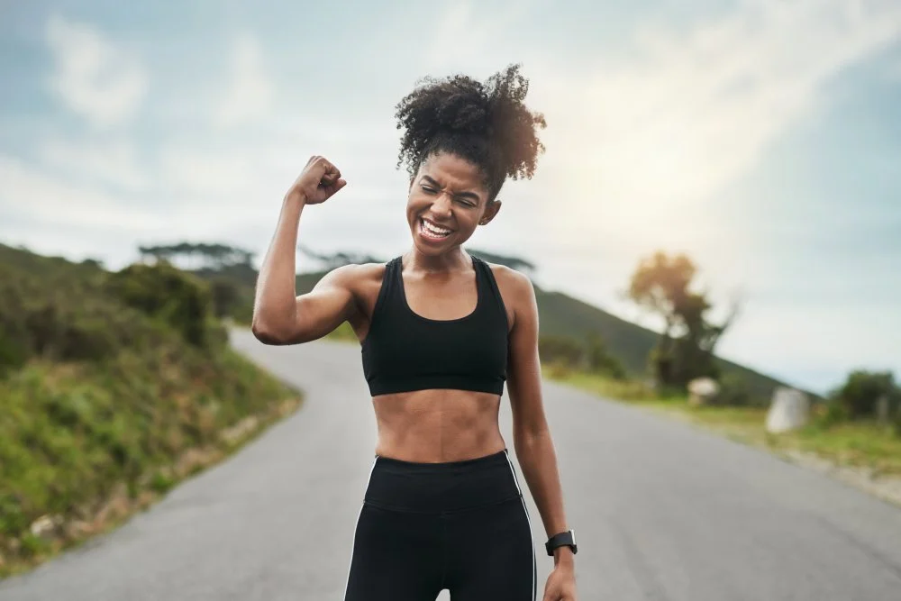 Woman with firm, toned skin flexing on a country road – the lifted look supported by WellFit Lift.