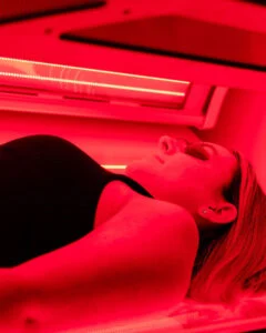 Customer using a full-body red light therapy booth after a WellFit spray skincare session at The Tanning Shop.