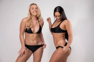 Two smiling women in black swimwear showcasing the natural-looking, bronzed results of a Norvell spray tan. Two smiling women in black swimwear showcasing the natural-looking, bronzed results of a Norvell spray tan.