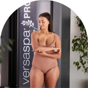 Woman With Tanned Skin In Front Of The Versaspa Pro Spray Tan Booth At The Tanning Shop Ireland